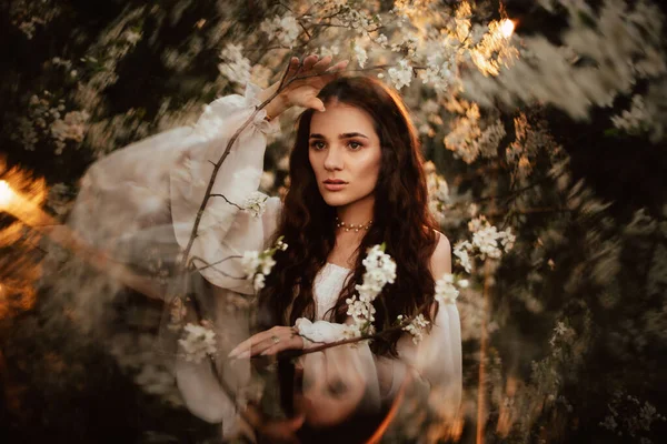 ファンタスマゴリアの要素を持つ開花庭で、森のニンフのようなロマンチックな女の子の肖像画。ファンタジーやメルヘンの概念. — ストック写真