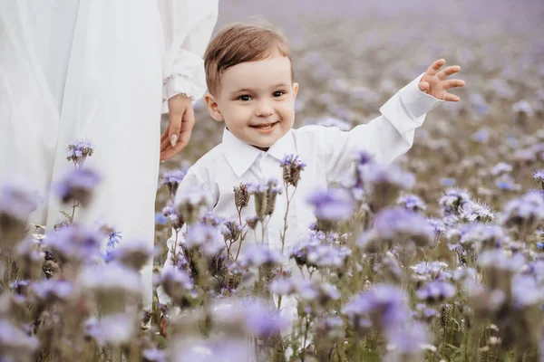 Glad leende pojke löper genom ett blommande fält — Stockfoto
