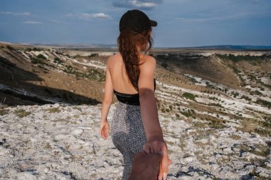 Genç bir bayanla birlikte beni takip edin. Bir yolcuyu dağlık bir alana götürüyor. Gökyüzünün altındaki dağ manzarası