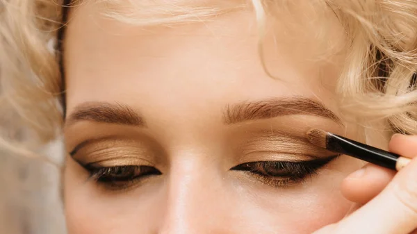 Een make-up kunstenares doet een model oogmake-up. Schieten in een schoonheidssalon. Close-up. — Stockfoto