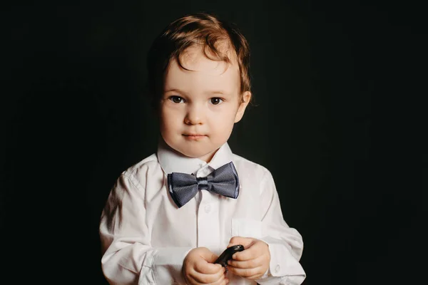 Portrait d'un petit garçon sur fond sombre en chemise blanche et noeud papillon — Photo