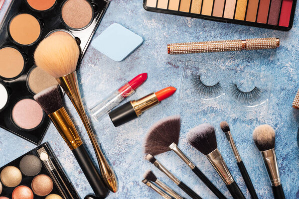 set of decorative cosmetics, makeup brushes on a blue background. the view from the top