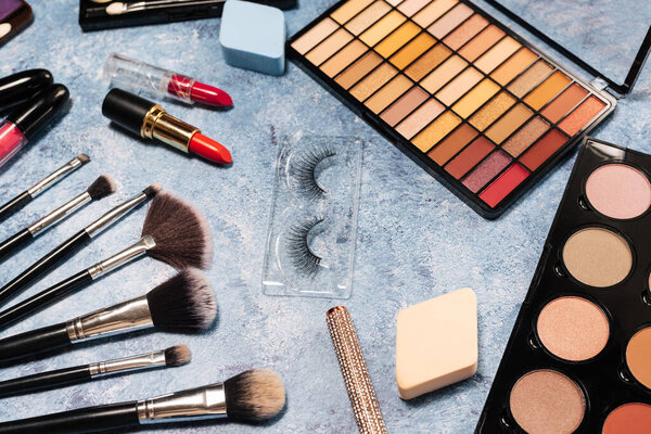 set of decorative cosmetics, makeup brushes false eyelashes on a blue background. the view from the top