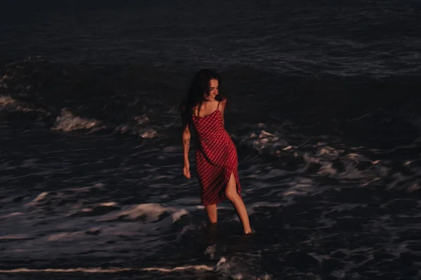 夏の夜、波に乗って海岸線を歩いている若い女の子。自由の概念. — ストック写真