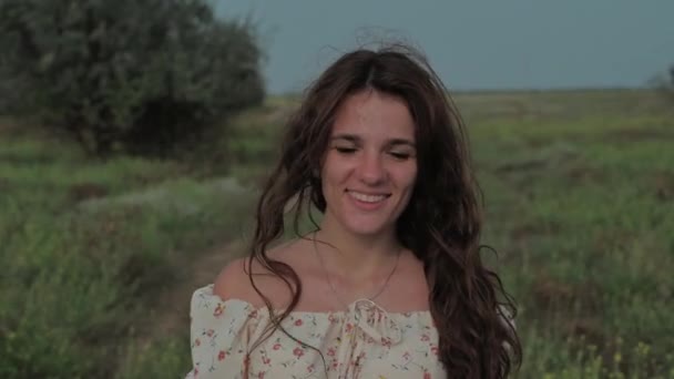 A beautiful girl in the steppe. Slow-motion authentic video. A beautiful young girl sincerely laughs and smiles at the camera. — Stock Video