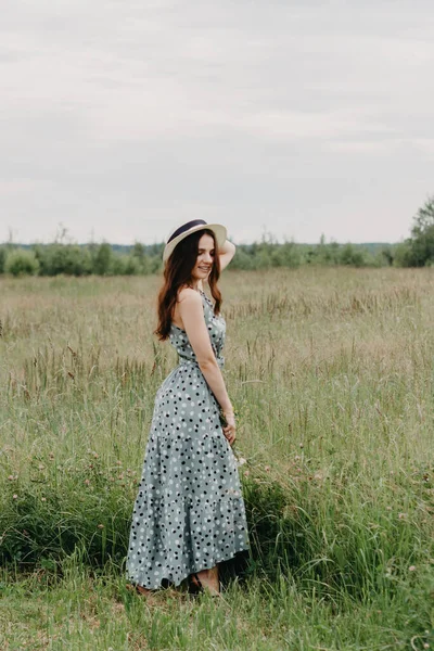 Una ragazza con un cappello di paglia in un campo verde estivo — Foto Stock