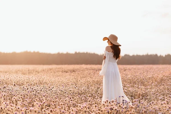 Mooi meisje in een wit jurk in een lavendel veld bij zonsondergang. — Stockfoto