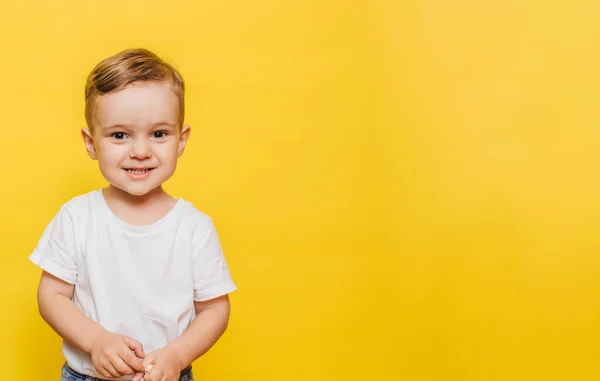 Retrato de um menino rindo bonito em um fundo amarelo. Espaço de cópia. — Fotografia de Stock