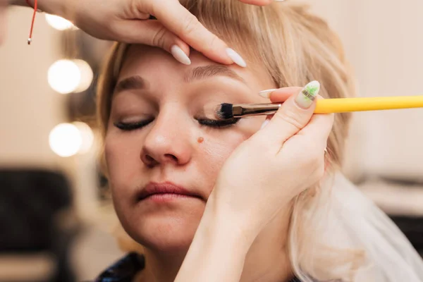 Een vrouwenhand brengt oogschaduw aan met een make-up borstel. — Stockfoto