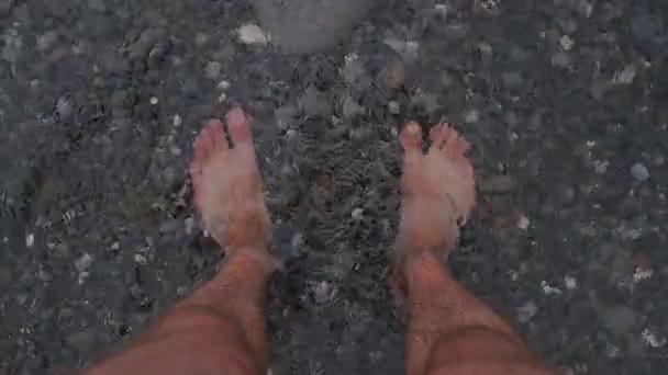 Hombres piernas bronceadas están de pie en el mar. Son lavados por las olas. El concepto de relajación y vacaciones de verano. Un vídeo en cámara lenta — Vídeos de Stock