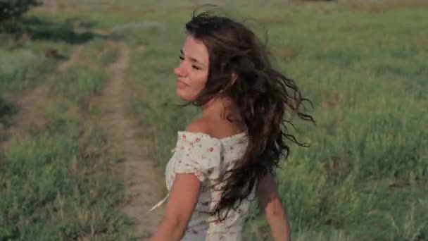 A beautiful girl in the steppe. Slow-motion authentic video. A beautiful young girl is circling and sincerely smiling at the camera. — Vídeos de Stock