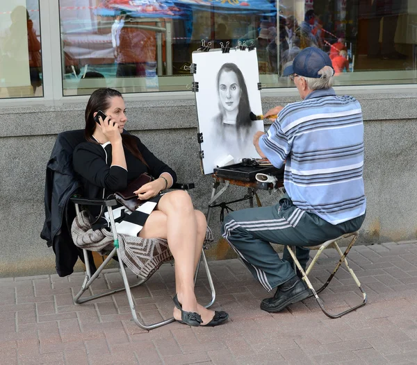 Street artist draws a girl on the Arbat