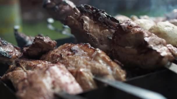 Trozos grandes de carne en un pincho en el humo de la parrilla. una mano de hombre da vuelta la carne — Vídeo de stock