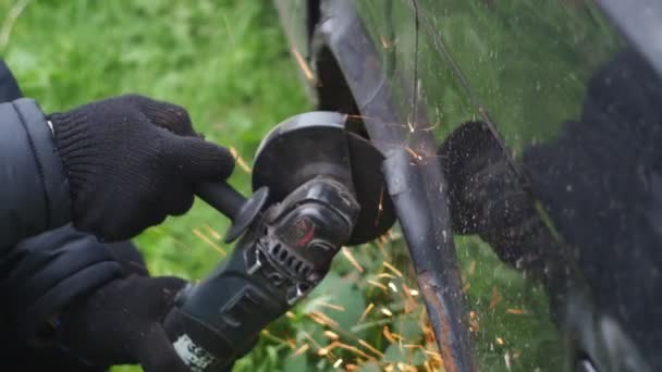 Un hombre con guantes sierra metal con un disco de corte. amoladora angular. trabajando con metal. salpicaduras brillantes ardientes. cortando el coche. mecánico de las obras de montaje mecánico — Vídeos de Stock