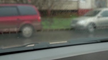 Yağmur damlaları arabanın camından aşağı aktı. Yağmur yağıyor, dışarıda kötü hava var. Su akıntısı. Silecekler bardaktaki suyu temizler.