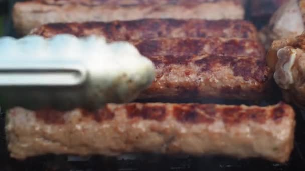Con le pinze, gira le salsicce fritte sulla griglia sui carboni. kupaty acquisire un colore fritto — Video Stock