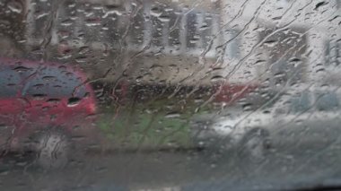 Yağmur damlaları arabanın camından aşağı aktı. Yağmur yağıyor, dışarıda kötü hava var. Su akıntısı. Araba otoparkta.