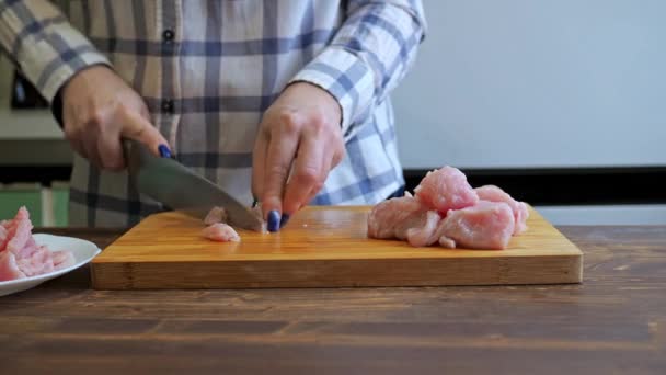 Una mujer corta un filete de pavo en una tabla de madera de corte. cocinar en la cocina. proteína dieta alimentos — Vídeos de Stock