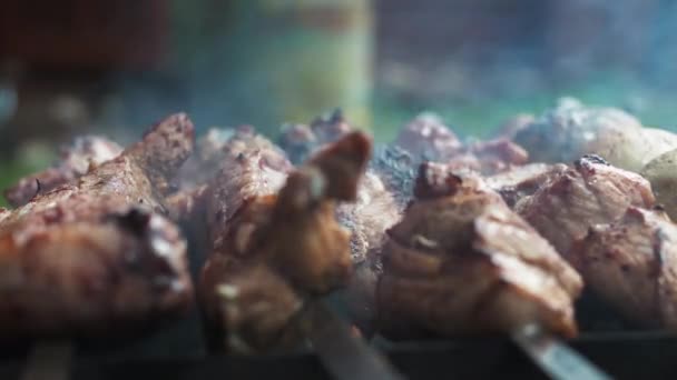 Trozos grandes de carne en un pincho en el humo de la parrilla. una mano de hombre llena la carne con cerveza de una lata — Vídeo de stock