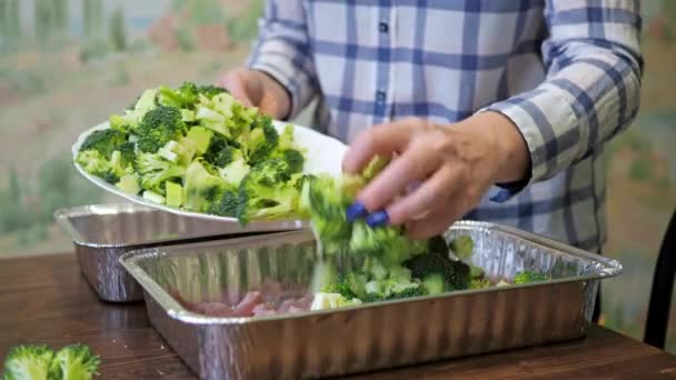 Una donna mette dei broccoli affettati sulle teglie. alimentazione sana. una donna in camicia. cottura — Video Stock