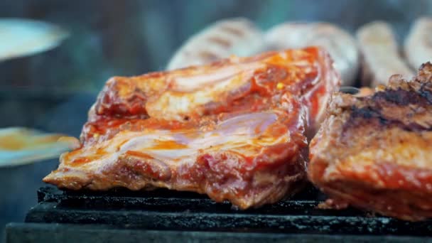 Schweinerippchen werden mit einer Zange auf dem Grill umgedreht. der Rauch der Kohlen. Kochen auf dem Grill. Nahaufnahme — Stockvideo