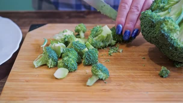 Kvinnors händer skär broccoli på en skärbräda med kniv. hälsosam kost — Stockvideo