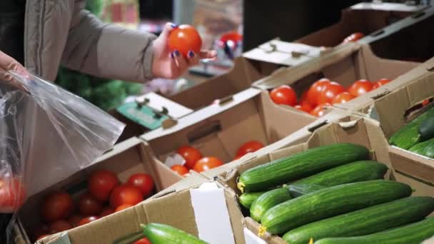Une vitrine avec des produits. une femme met une tomate dans un sac. supermarché épicerie, vente au détail — Video