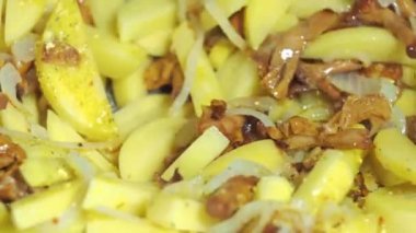 Mantar ve patates kızartma tavasında kızartılır. Tahta bir spatulayla karıştırmak. yemek yapmak