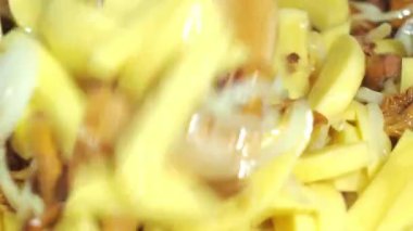 Mantar ve patates kızartma tavasında kızartılır. Tahta bir spatulayla karıştırmak. yemek yapmak