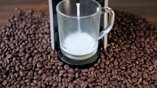 La leche se vierte de una máquina de café. hay granos de café en la mesa — Vídeos de Stock