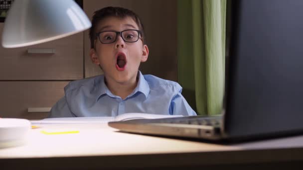 Afstandsonderwijs. Een tiener met een bril doet zijn mond open. online opleiding. close-up. kijkt naar de camera — Stockvideo