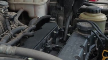 Bir adam tozlu bir araba motoruna buji takıyor. Araba tamiri. servic