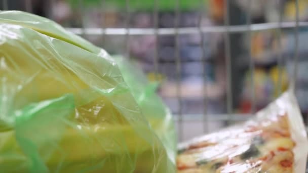 Σούπερ μάρκετ καλάθι τροφίμων έννοια τρόπο ζωής του προϊόντος καλάθι αγορών κατάστημα shopper shopper υπεραγορά αγορών. θέα από το καλάθι με τα ψώνια. πάρτε μπανάνες σε μια τσάντα και πίτσα — Αρχείο Βίντεο
