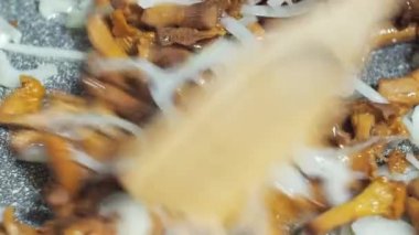 Mantarlı soğan kızartma tavasında kızartılır. Tahta bir spatulayla karıştırmak. yemek yapmak