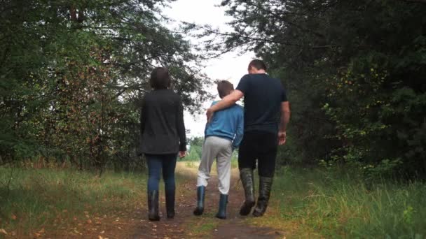 La familia está caminando en el bosque. vista desde atrás. 3 personas. madre, hijo y padre. el niño está jugando — Vídeos de Stock