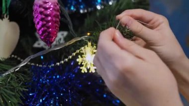 Noel ağacını yeni yıl balosuyla süsleyen çocukların elleri parlak festival ışıklarının arka planında. Çocuklar Noel ağacını süslüyor.