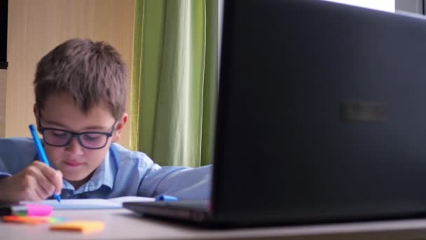 Video kursundan ev ödevi. Bir genç masada oturuyor ve bir deftere yazıyor. — Stok video