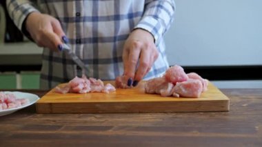 Bir kadın ahşap bir tahtanın üzerinde hindi filetosu kesiyor. Mutfakta yemek pişirmek. protein diyeti