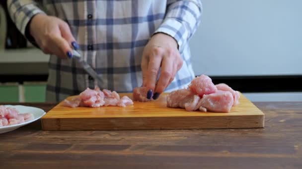 Una mujer corta un filete de pavo en una tabla de madera de corte. cocinar en la cocina. proteína dieta alimentos — Vídeo de stock