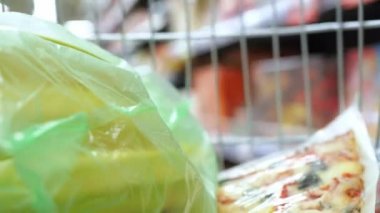 Süpermarket gıda arabası konsept alışveriş arabası alışveriş mağazası alışverişçisi market hipermarketi. Market arabasının manzarası. Muzu ve pizzayı poşete koy.