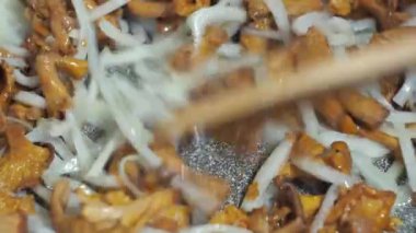 Mantarlı soğan kızartma tavasında kızartılır. Tahta bir spatulayla karıştırmak. yemek yapmak