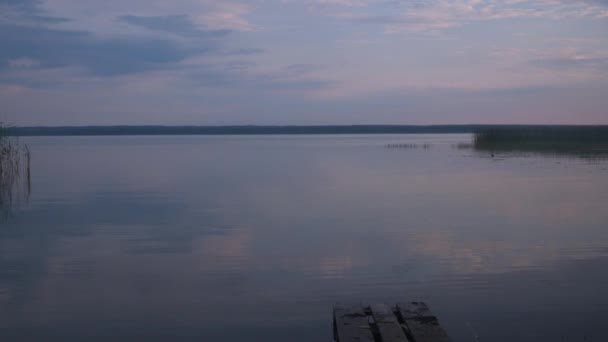 Tranquillità del lago. una piccola onda sull'acqua. la luce soffusa del sole tramontante si riflette nell'acqua. posti bellissimi del pianeta. un piccolo ponte in primo piano — Video Stock