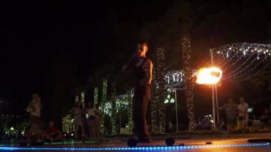 Yalta 2021.08.25. Barajdaki yangın gösterisi. Bir adam ateşle dans eder. Boynuna bir ateş topu dola. Etrafta bir sürü insan var.