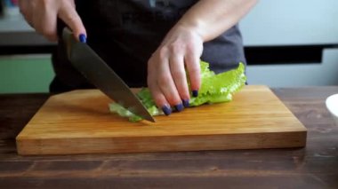 Yakından yeşil salata dilimliyorum. Kadınların elleri bıçakla sebze keser. Yunan salatasının hazırlanması