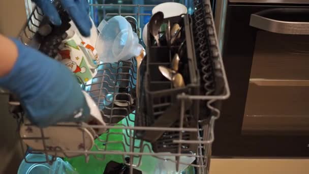 Жіночі руки викладають брудний посуд у посудомийній машині. домашнє завдання — стокове відео