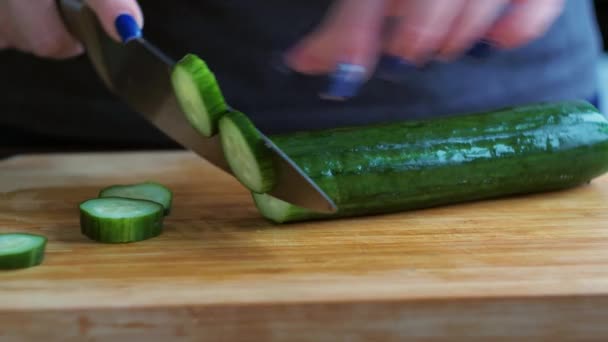 Нарезаю огурец крупным планом. Женщины руками режут овощи ножом. приготовление греческого салата — стоковое видео