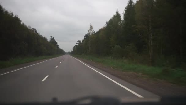 Una strada nella foresta autunnale. vista dalla macchina. viaggiare in auto. ripresa dal sedile del conducente — Video Stock