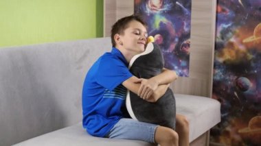 Çocuk oyuncak penguene sıkıca sarılıyor. Çocukluk anıları. neşeli duygular. yumuşak oyuncaklar. Rebonka 'nın kollarında Kowalski