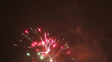 Gece gökyüzünde parlak renklerle havai fişekler patlıyor.
