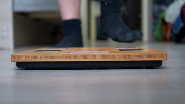De benen van een tiener in een sportuniform staan op de weegschaal. weegschaal in close-up focus — Stockvideo